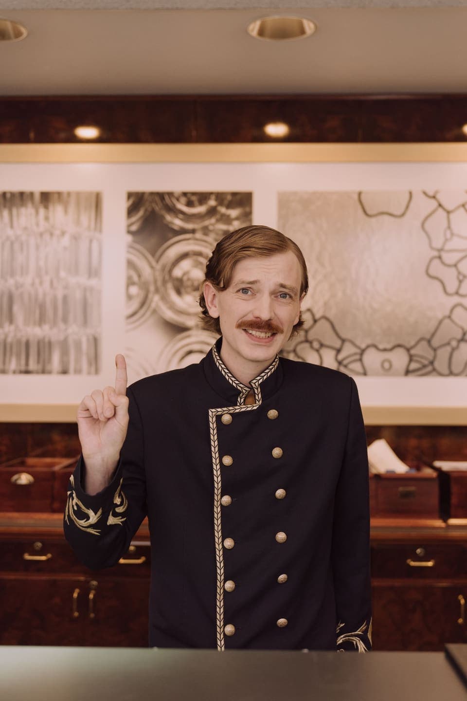 A smiling concierge in uniform at a hotel front desk